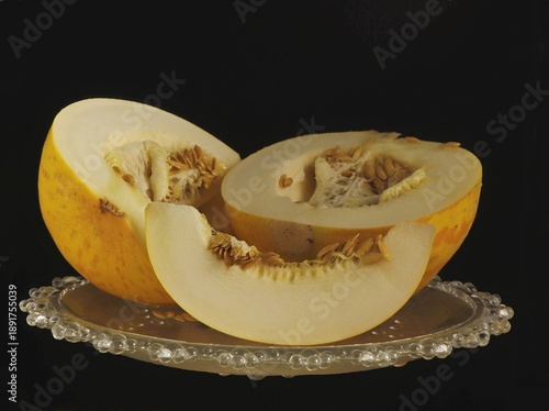 Image of a cut melon on a plate on a dark background.