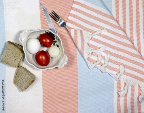 A plate with tomatoes and bread on a tablecloth, top view.