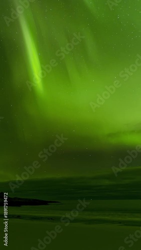 Northern Lights, aurora borealis over sandy beach surrounded by mountains. 4K  4K Vertical 9:16 Time Lapse. Lofoten Islands, Northern Norway
