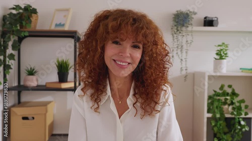 POV camera view or front portrait of happy attractive businesswoman at the office. Smiling headshot of mid adult woman smiling at camera from home office. 