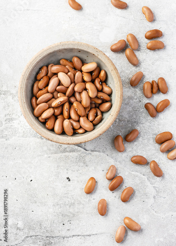 Top view of dried “Canela” cinnamon beans (Phaseolus vulgaris) in a clay bowl. Minimalist composition, plant-based protein, organic farming, and healthy nutrition, with copy space.