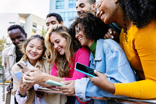 Diverse student group hanging out in city park using mobile phones. Multiracial young friends enjoying social media on cellphones outdoors. Technology and youth lifestyle concept