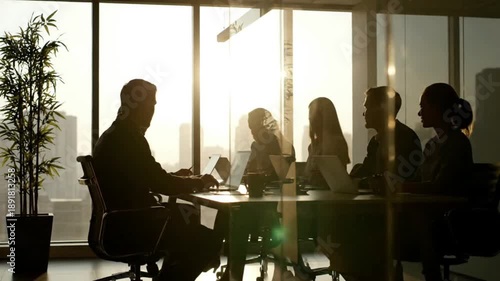 Silhouetted business professionals in a modern office meeting room, collaborating and discussing strategies with laptops against a bright window and city view. 4k Video