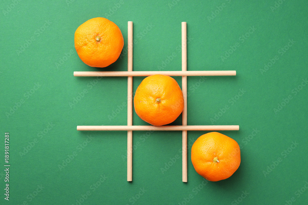 Obraz premium Tic tac toe game made with oranges on green background, flat lay
