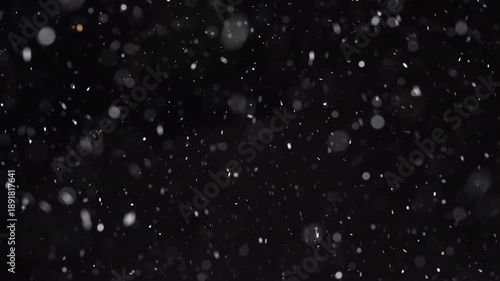 Abstract winter background with falling snow on a black backdrop. Blurred snowflakes, ice particles, and bokeh motion create a cinematic blizzard effect for Christmas, New Year, and seasonal overlays.