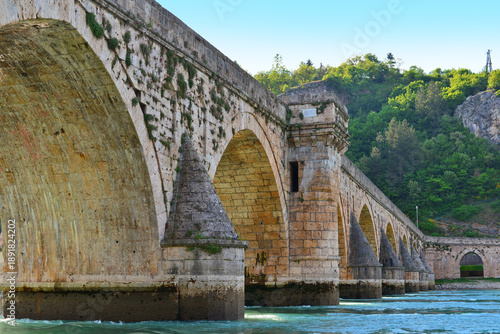 Famous Mehmed Pasha Sokolovic Bridge crossing the Drina River in Visegrad, Bosnia and Herzegovina, traditional stone arches reflected in peaceful landscape.