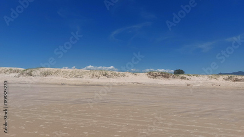 White sand dunes on the beach with blue sky and white clouds