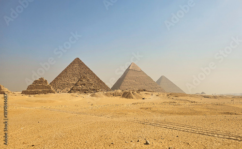 Wide panoramic view of the Great Pyramids of Giza under a clear blue sky, showcasing ancient Egyptian architecture and the vast desert landscape near Cairo, Egypt.