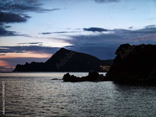 Calm ocean with distant silhouette, Peaceful scenery featuring reflective seas and cloudy sky background
