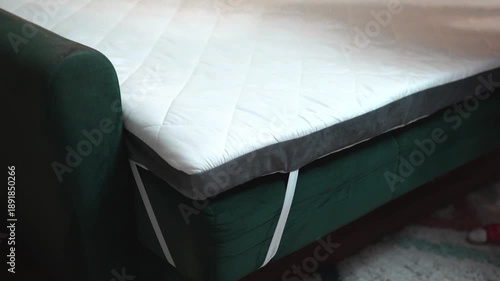 Man setting up a folding mattress  topper for sofa.  White quilted mattress for comfort sleeping on a couch.