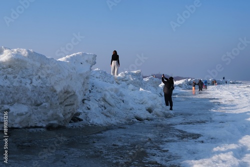 Wallpaper Mural Ice toros (mountains of piled-up ice) on the beach in Mikoszewo, Baltic Sea, Pomerania, Poland. This is a very interesting and rare phenomenon. Silhouettes of people walking and taking photos. Torontodigital.ca
