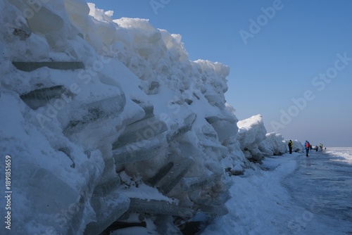 Wallpaper Mural Ice toros (mountains of piled-up ice) on the beach in Mikoszewo, Baltic Sea, Pomerania, Poland. This is a very interesting and rare phenomenon. Silhouettes of people walking and taking photos. Torontodigital.ca