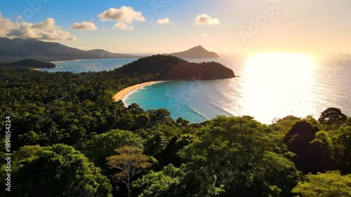 Breathtaking scenic view of a tropical paradise with a hidden beach, lush green trees, and the ocean during golden hour