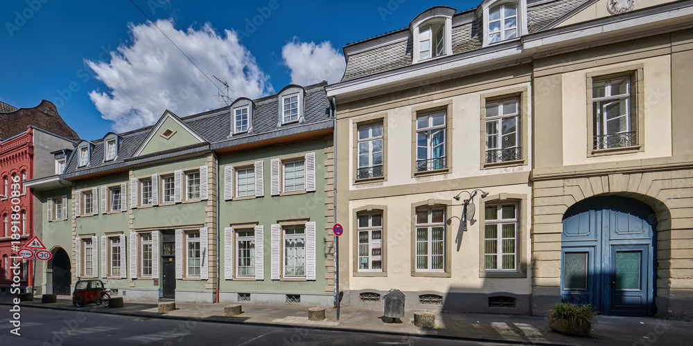 Obraz premium A row of colorful historic townhouses with shutters at Freiheit in Cologne-Muelheim under a bright blue sky