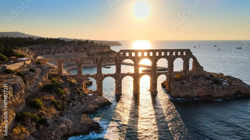 Ancient Roman aqueduct bridge in Tipasa Algeria at sunrise with reflections on the water