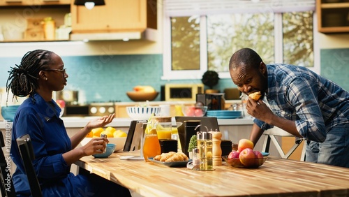 Photos African american man in a hurry running late for his office job, skipping breakfast and leaving his housewife to eat alone at the table