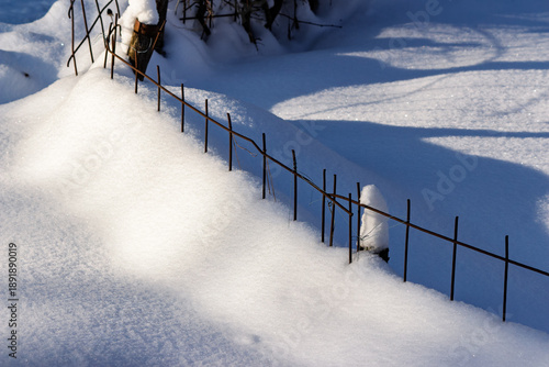 Wallpaper Mural A rustic garden fence barely peeks above deep, glistening snowdrifts bathed in bright winter sunlight creating stark blue shadows Torontodigital.ca