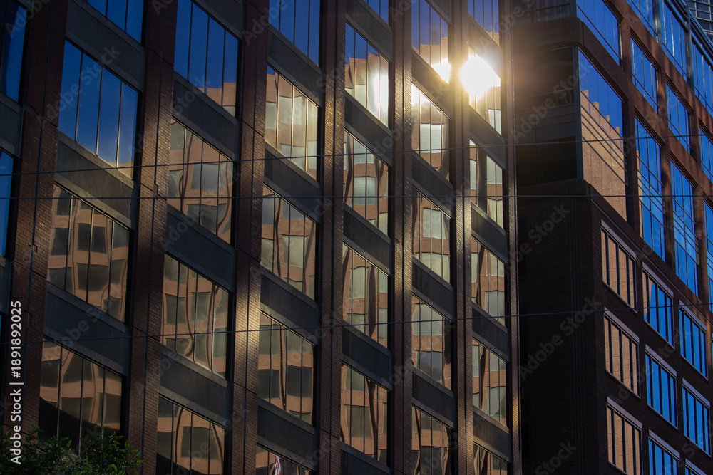 Fototapeta premium Sunlight reflecting off glass facade with geometric patterns in urban architectural scene