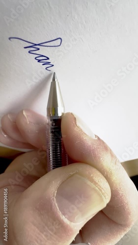 Person handwriting the word handwriting in cursive script in close up