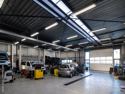 Automotive workshop specializing in electric vehicle repair and maintenance, multiple EVs being serviced by technicians