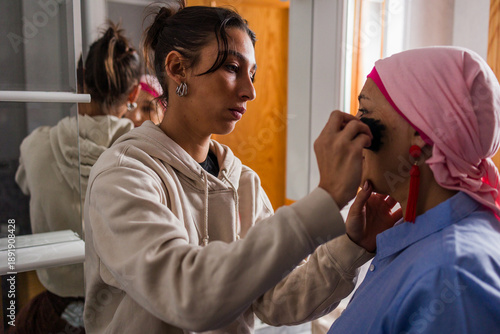 Daughter helping mother with cancer applying makeup