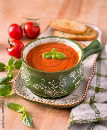 Bowl of fresh raw tomato soup with toasted bread and fresh basil; copy space