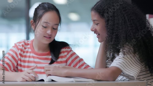Two female students are reading books together.