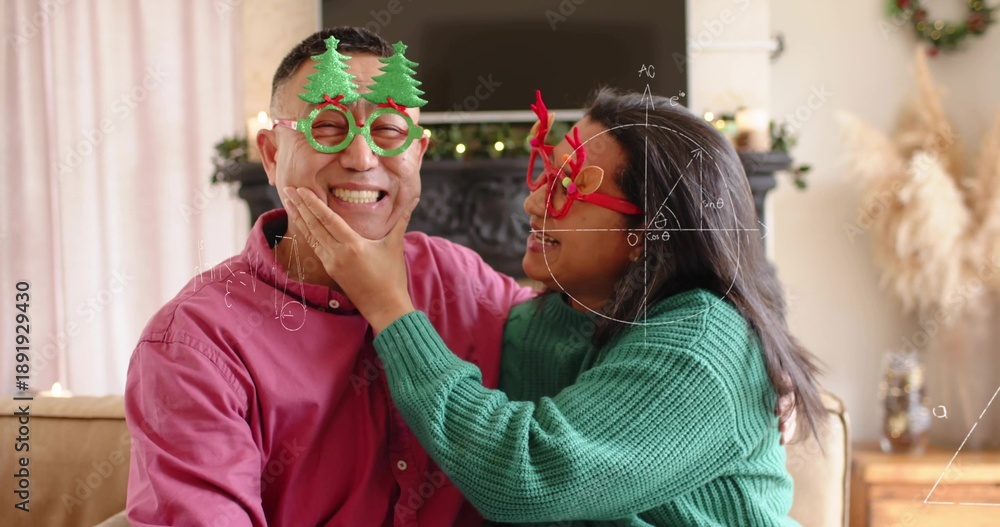 Fototapeta premium Smiling couple cupping chin, wearing green knit sweater and red shirt with novelty glasses at home
