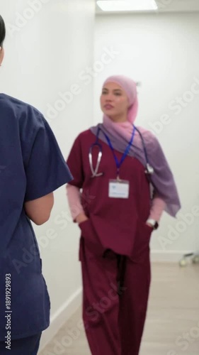 Vertical video: Walking down corridor nurse in maroon scrubs giving update and showing stethoscope