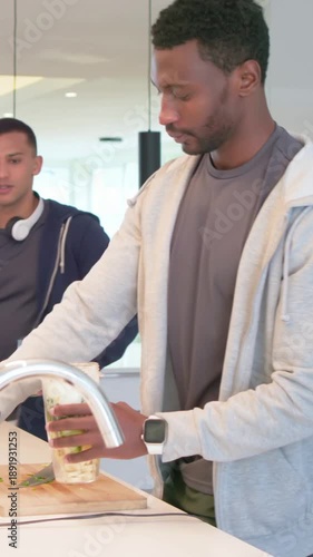 Vertical video: Placing cup on board, man in grey hoodie locking cup into motor base making drinks