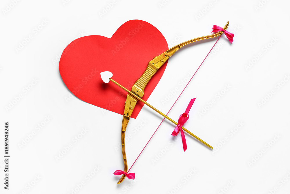 Fototapeta premium Cupid's bow and red paper heart on light background. Valentine's Day celebration