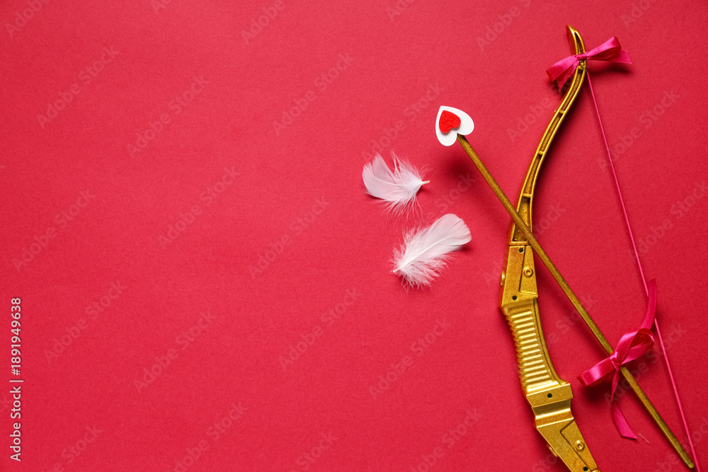 Obraz premium Cupid's bow, arrow and feathers on red background. Valentine's Day celebration