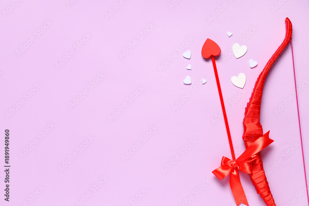 Fototapeta premium Composition with cupid's bow, arrow and paper hearts on lilac background. Valentine's Day celebration