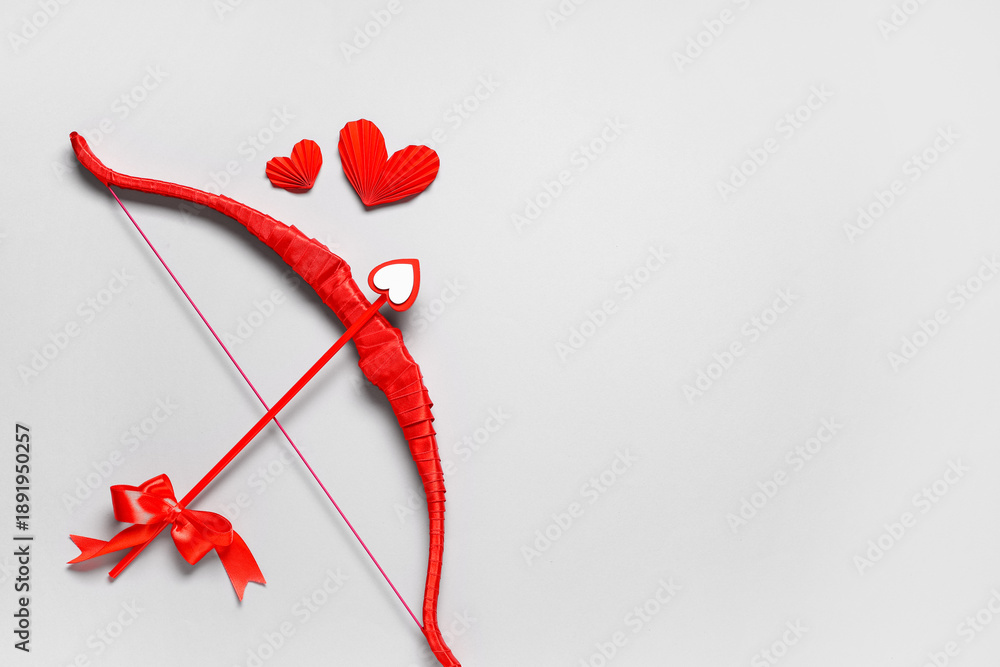 Fototapeta premium Red cupid's bow and paper hearts on grey background. Valentine's Day celebration