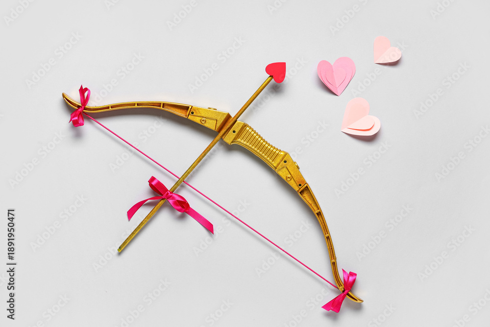 Fototapeta premium Composition with cupid's bow and paper hearts on grey background. Valentine's Day celebration