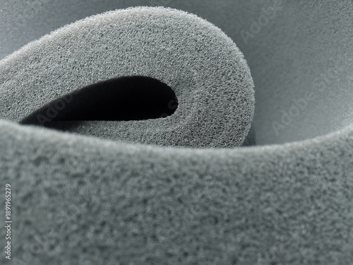 extreme close-up of the beautiful folds of gray sponge foam material with a porous structure and curved shape. synthetic material as a cushion, damper
