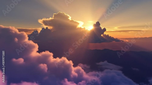 Epic sunrise aerial view of the sun shining through fluffy clouds with stunning rays of light over mountains