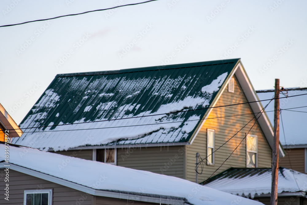 Fototapeta premium A green, steel roof covered in snow during winter