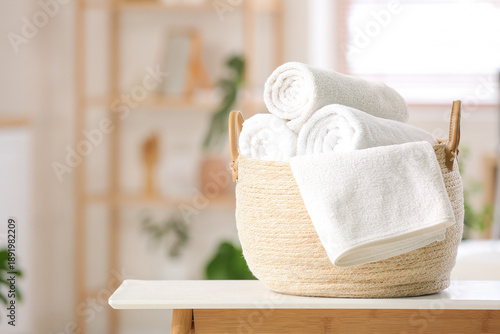 Photos Basket with clean soft rolled towels on table in bathroom