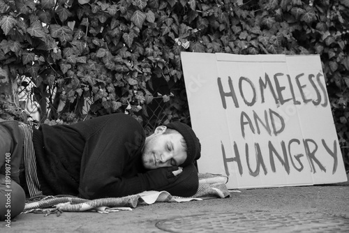 Homeless man with cardboard sleeping on street