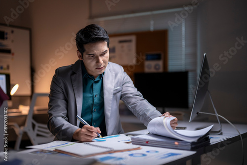 Fotografi Asian businessman working extra hours preparing office paperwork