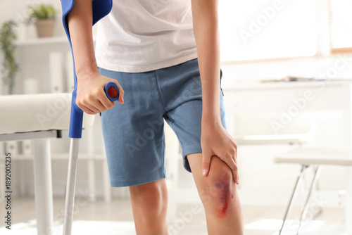 Little boy with injured knee and crutch in clinic, closeup