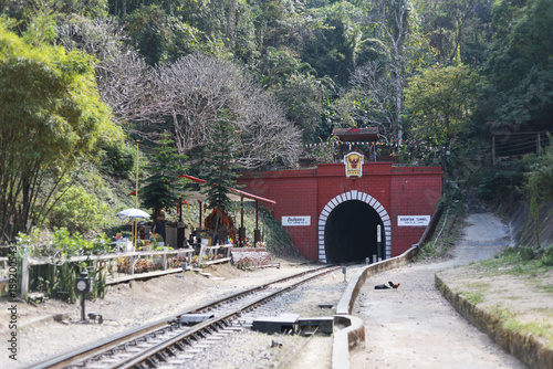 Scenic view of historic red railway tunnel entrance in green forest mountain pass. This old landmark offers nostalgic and adventurous travel journey through nature