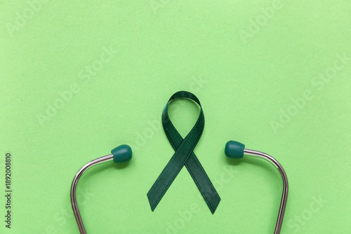 Valokuva Satin green ribbon and stethoscope on color background