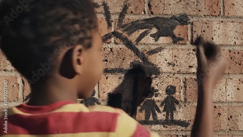Young boy drawing family and sun on brick wall.