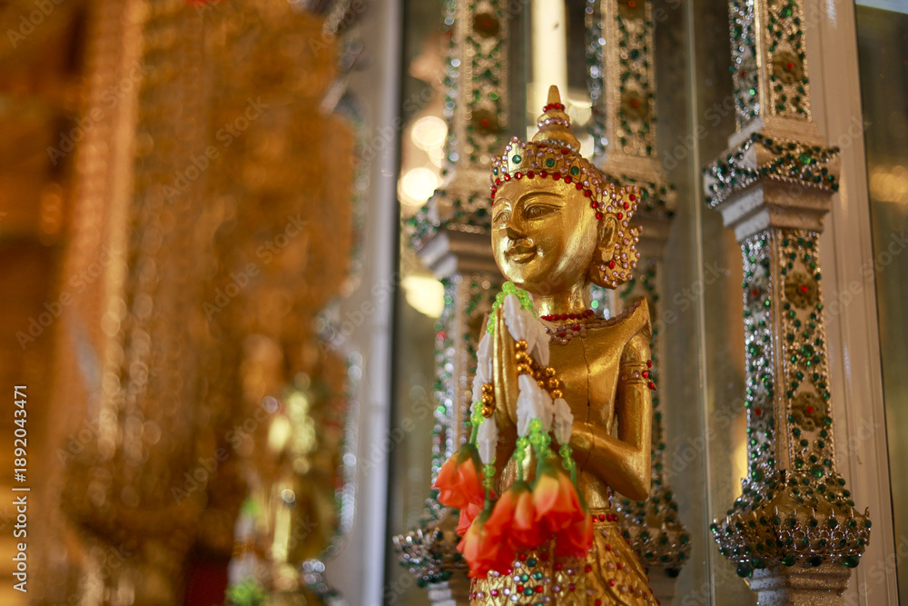 Fototapeta premium Serene golden statue of Buddha with gentle smile. Beautiful sculpture and art inside traditional temple in Asia. symbol of faith, peace, and religion