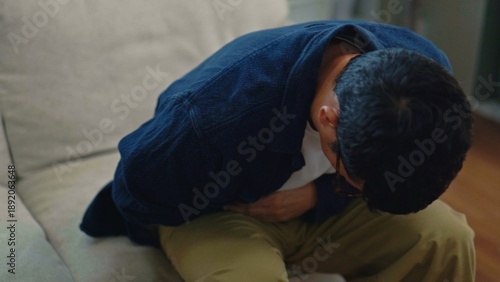 Obraz na płótnie Asian Man Suffering from Stomach Pain and Abdominal Cramps on Sofa at Home