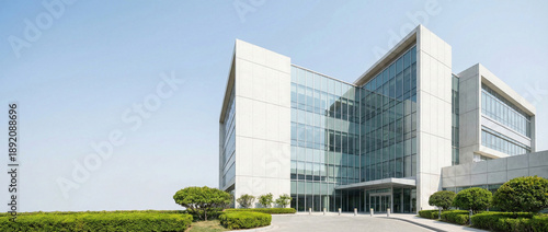 Contemporary glass office building or hospital research center architecture against blue sky, corner view with landscaping.