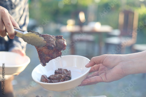 The party was held in the backyard in the evening as the sun was setting. The atmosphere was joyful and fun. Everyone helped prepare the food, including grilling meat, and alcoholic drinks were served