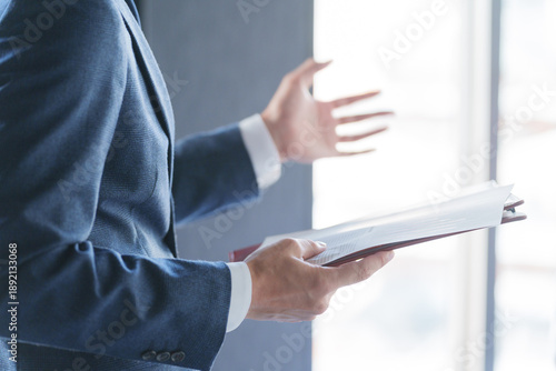 会議で紙資料を見てプレゼンテーションする男性ビジネスマン